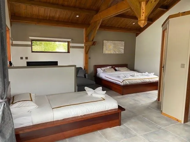 Intérieur du bungalow : lit double et lit simple, charpente bois apparente, grands volumes clairs