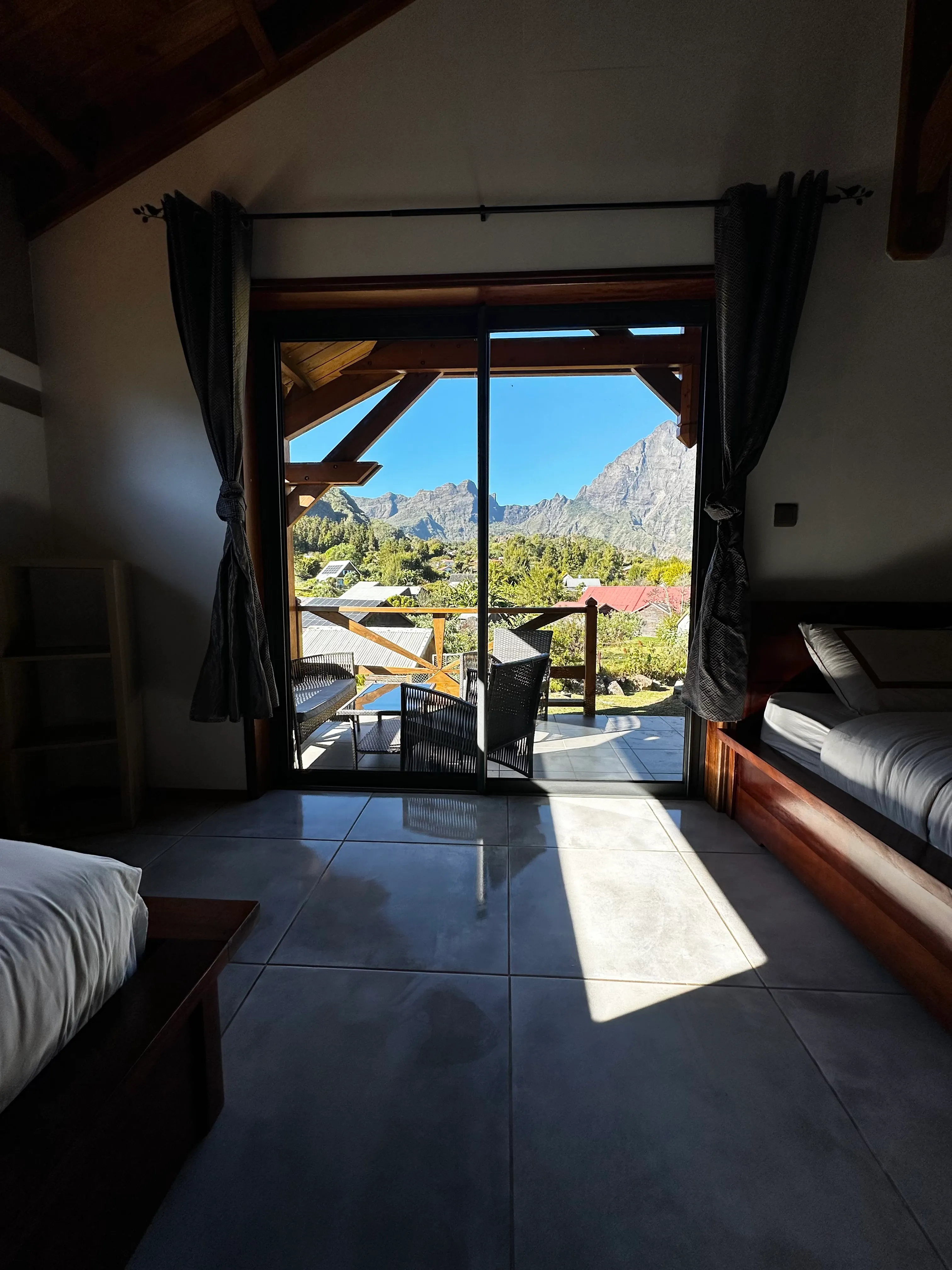 Baie vitrée du bungalow ouvrant sur la terrasse, face aux montagnes du cirque
