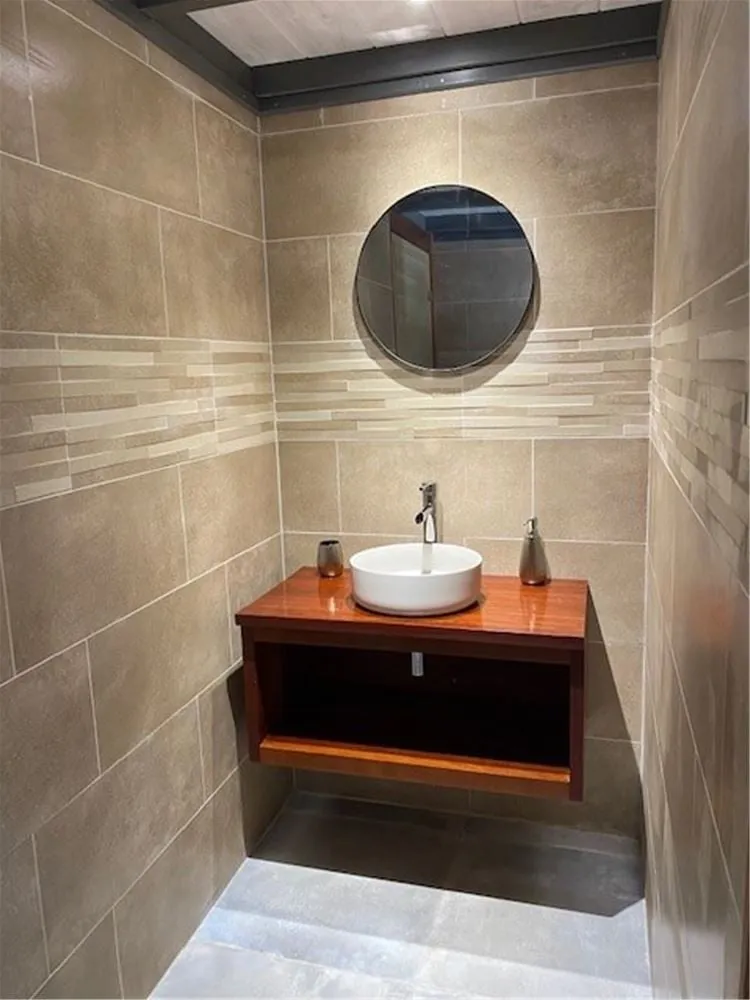 Salle de bain privative du bungalow : vasque sur meuble en bois et miroir rond