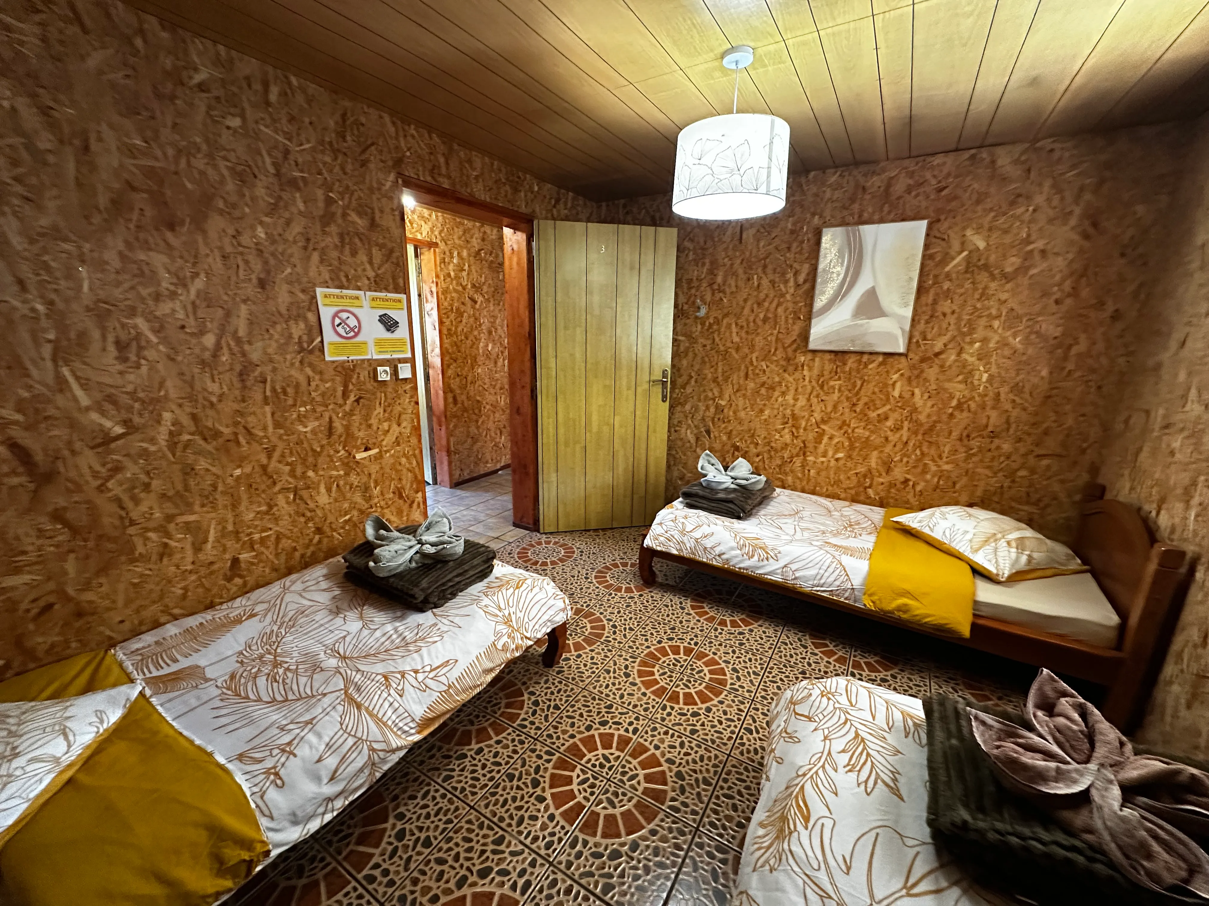 Dortoir 3 places : lits simples en bois sous les combles