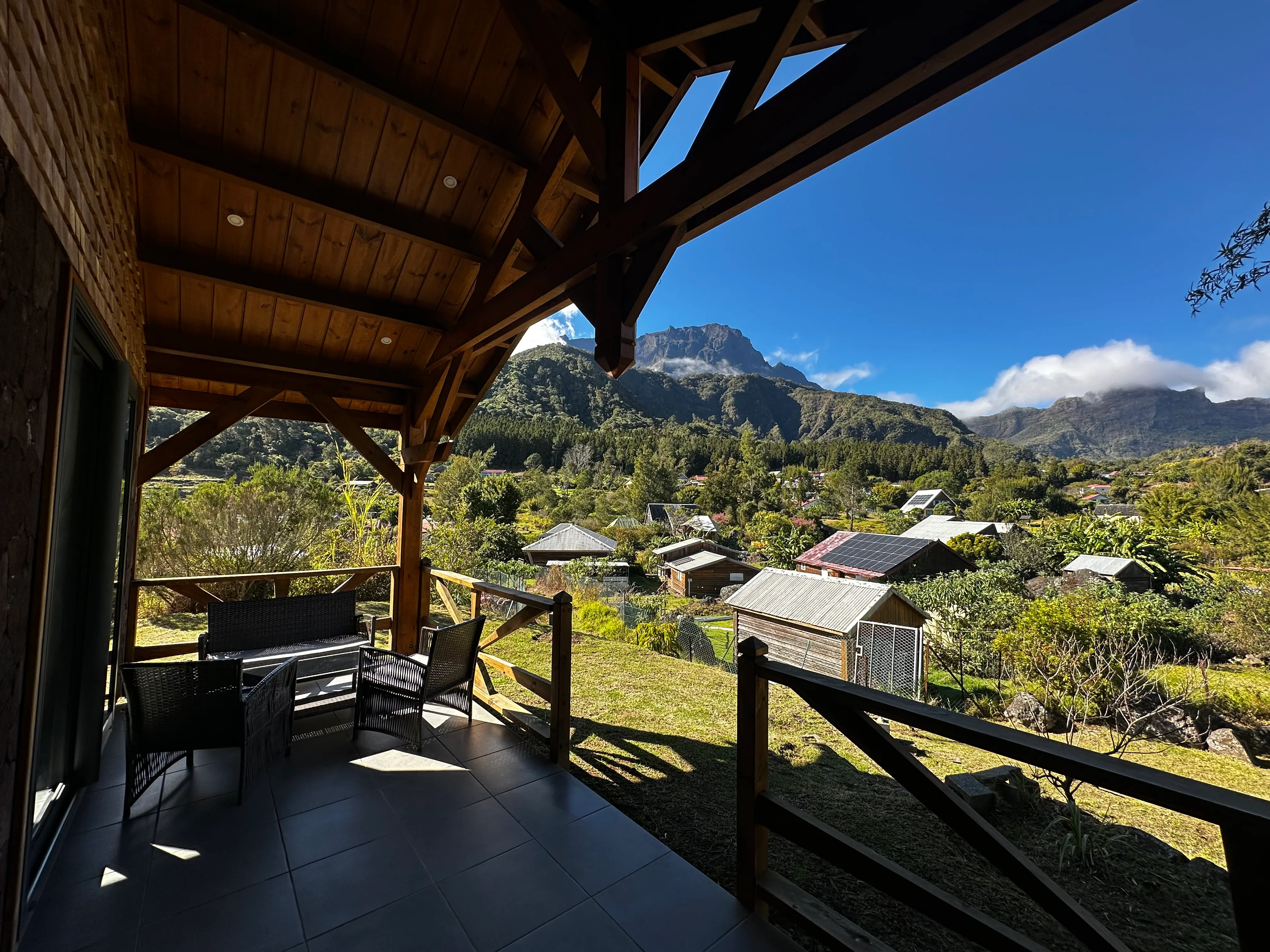 La vue depuis la terrasse couverte du gîte : les toits de La Nouvelle, la forêt et les remparts du cirque sous un ciel bleu