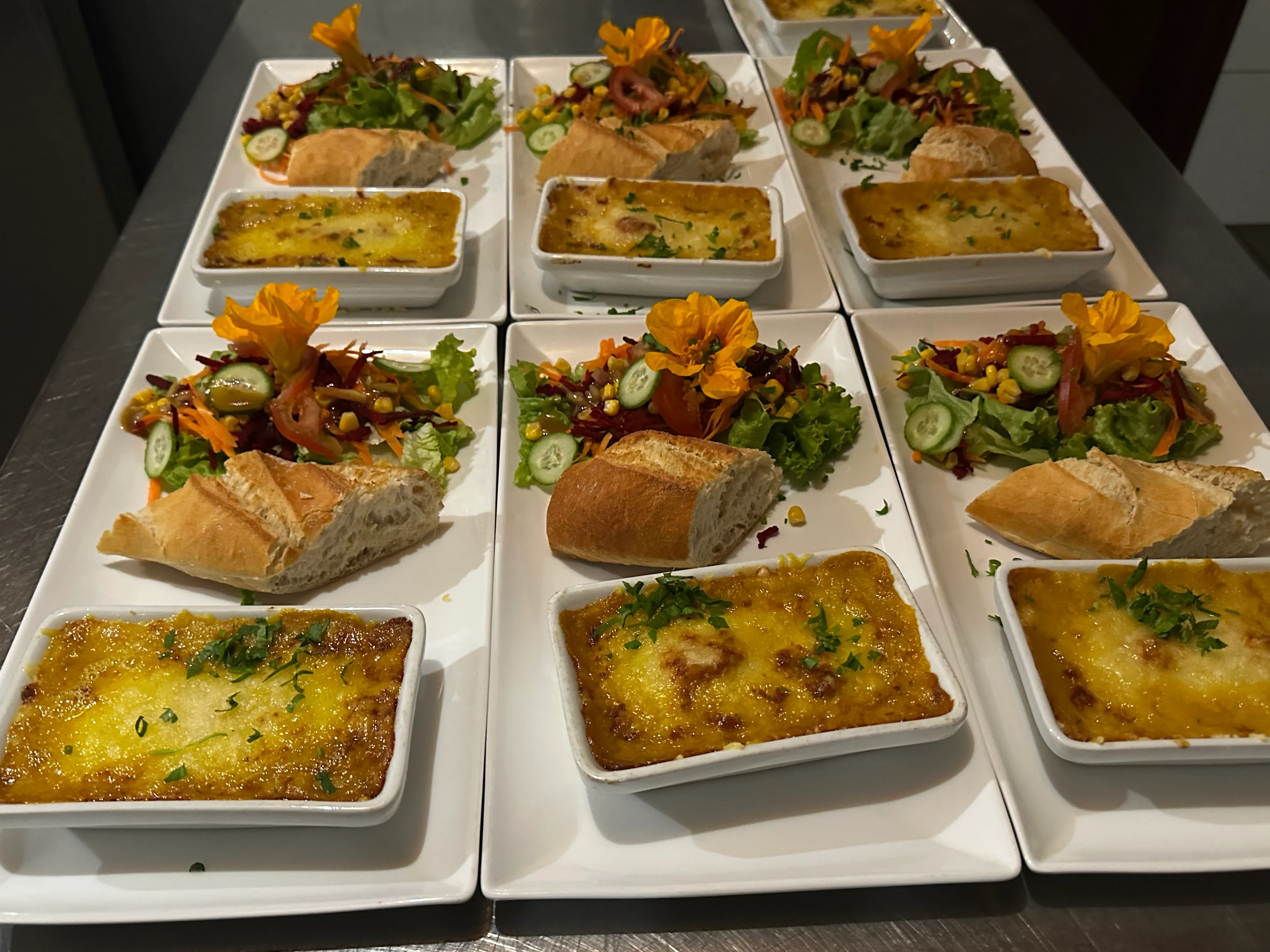Assiettes de la table d'hôte : gratins dorés, salades fraîches et pain